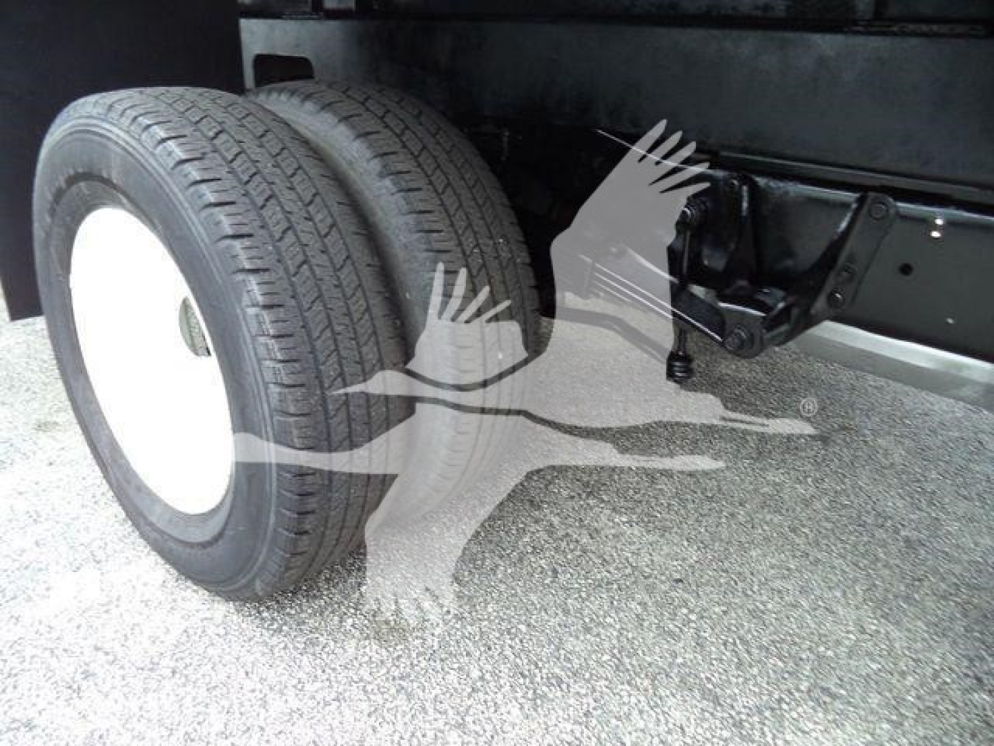 Ford E-450 chassis showing dual rear wheels and suspension hitch area with visible frame and tire tread.
