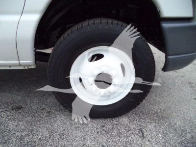 Ford E450 wheel area showing front tire and white steel wheel, partial front fender and splash guard.