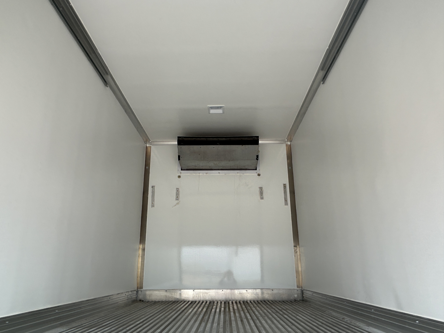 Refrigerated truck cargo area of a 2026 Mack MD6 showing interior walls and a rear door with a dark mechanism at top center.