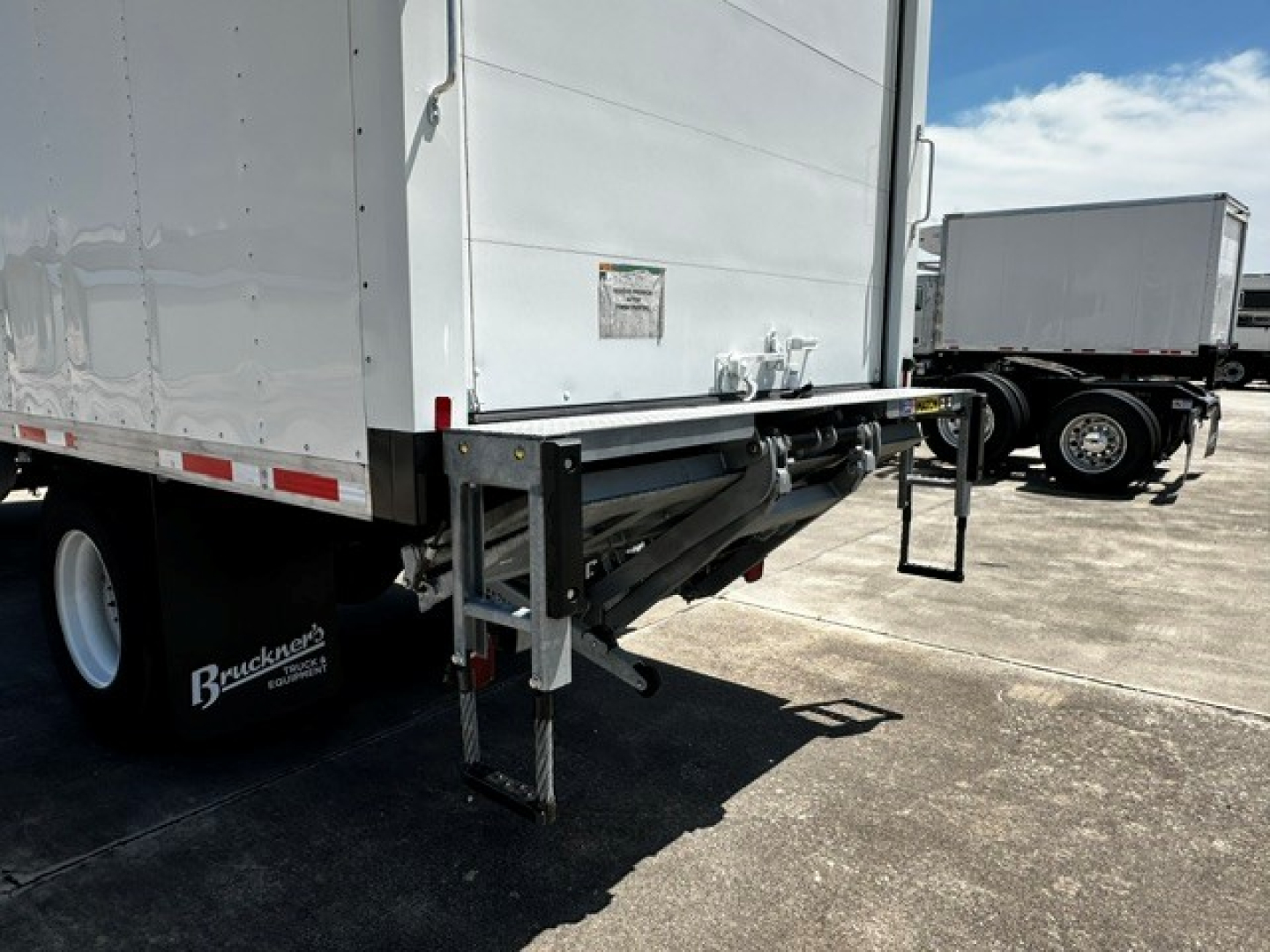 Truck rear view of 2026 Mack MD6 refrigerated tractor-trailer with liftgate and landing gear visible.
