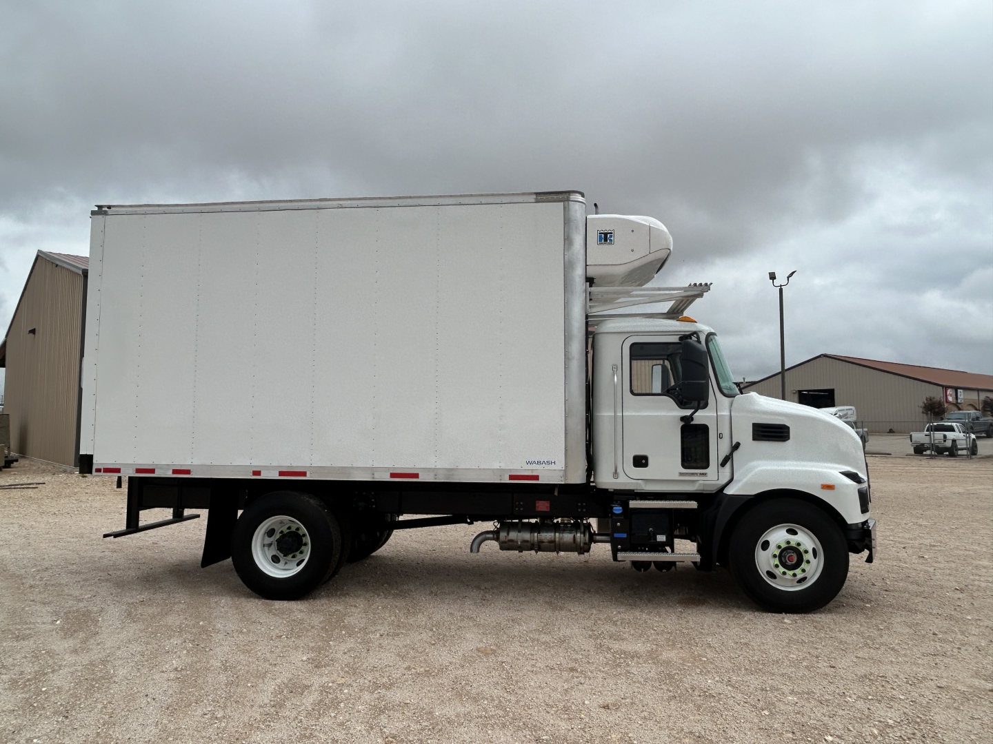 Mack MD6 refrigerated truck side view showing cargo box and refrigeration unit on cab roof with white exterior.