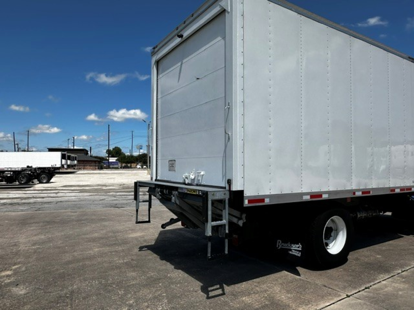 Rear view of a 2026 Mack MD6 refrigerated truck trailer showing side and back with a lift gate and white body.