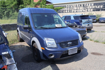 Ford Transit Connect cargo van in blue, front-left view with raised hood and windshield, number 63 on windshield, dealership lot in background.