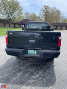 Rear view of a black 2013 Ford F-250 Super Duty pickup with a green license plate, visible Ford logo, tow hitch, and badge areas on tailgate.