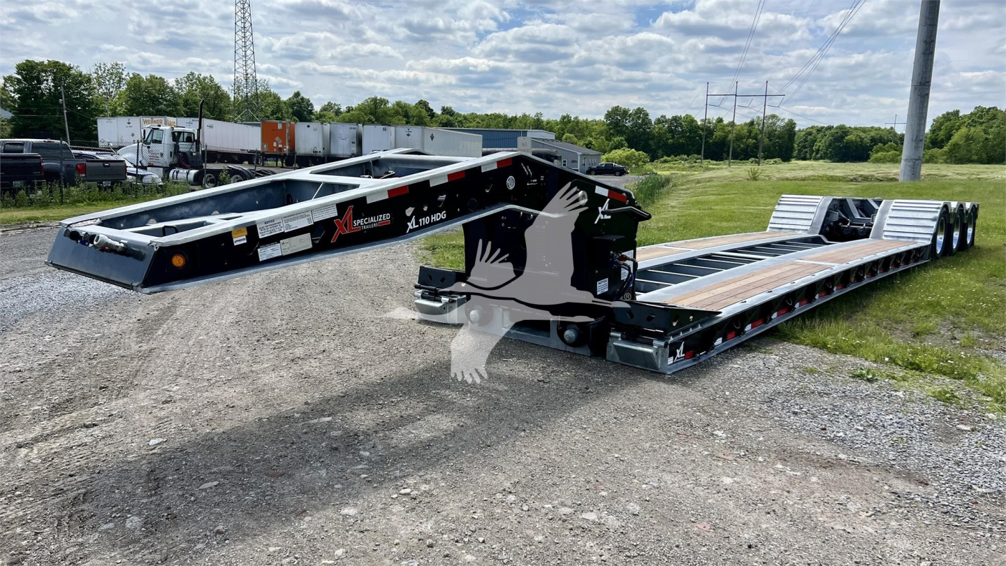 XL Specialized XL110HDGS lowboy trailer showing dual deck and gooseneck with black frame, white logos, and orange accents. Visible text: XL Specialized logo on side, lowboy rails, wooden deck sections.