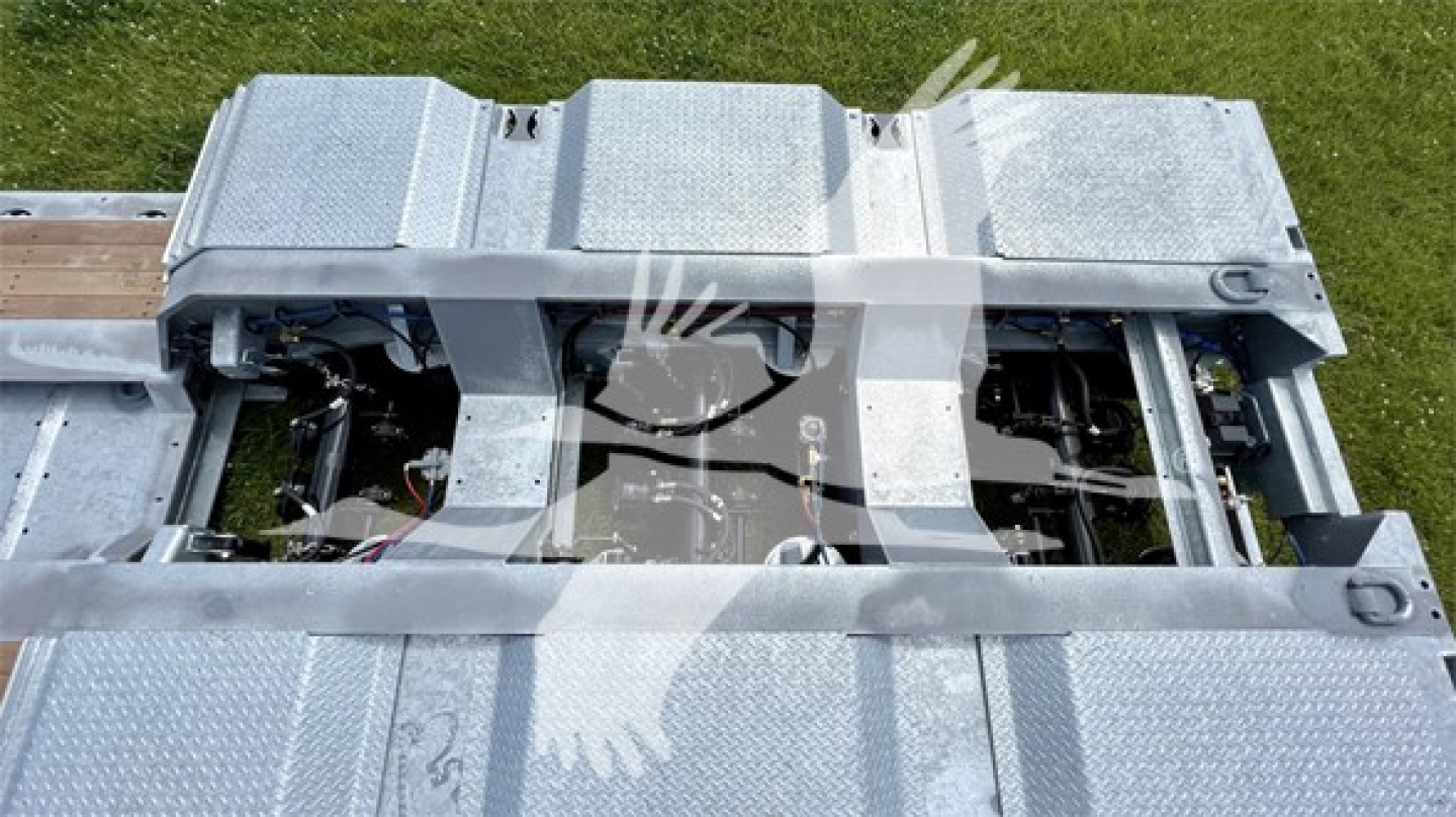 Trailer deck with visible metal diamond plate sections and exposed hoses/cables; no legible brand text or model numbers visible.