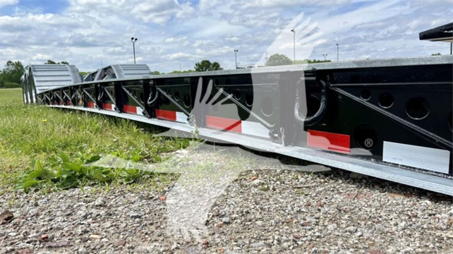 Lowboy trailer side rail showing structural frame with decals and reflective tape; black paint with white and red graphics on XL Specialized XL110HDGS trailer