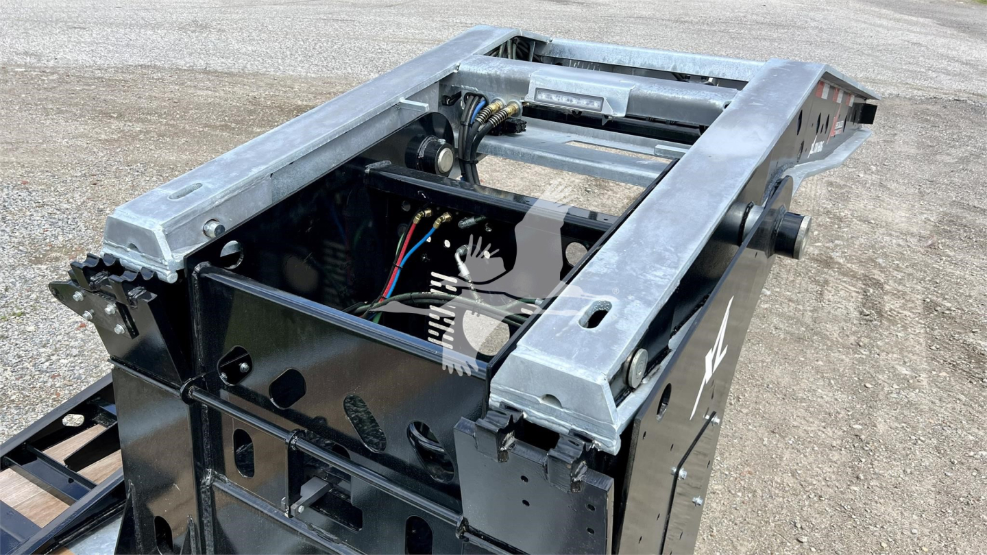 Trailer chassis showing hydraulic/electrical components and frame rails with wiring harness in a lowboy trailer base.
