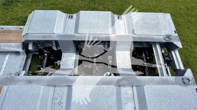 Trailer deck with visible metal diamond plate sections and exposed hoses/cables; no legible brand text or model numbers visible.