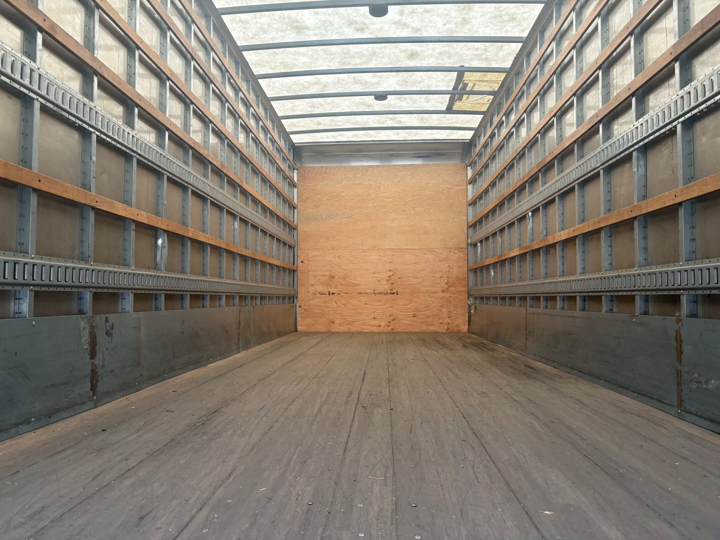 Kenworth box truck cargo area interior showing wood floor and metal side walls with rails, empty cargo space.
