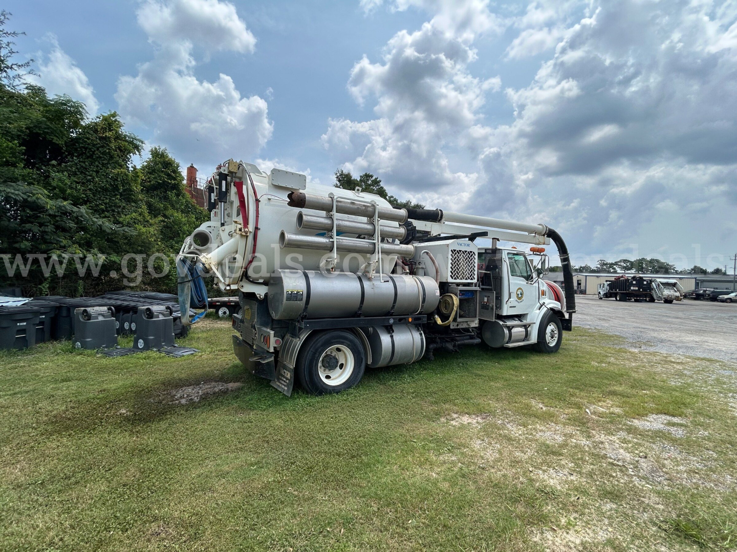 Sterling L7500 vacuum truck with mounted concrete pump equipment in a yard, side view showing hoses and tanks.