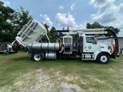 Side view of a used 2009 Sterling L7500 vacuum truck with mounted tank and long boom, tires, and engine bay visible.
