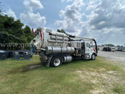 Sterling L7500 vacuum truck with mounted concrete pump equipment in a yard, side view showing hoses and tanks.