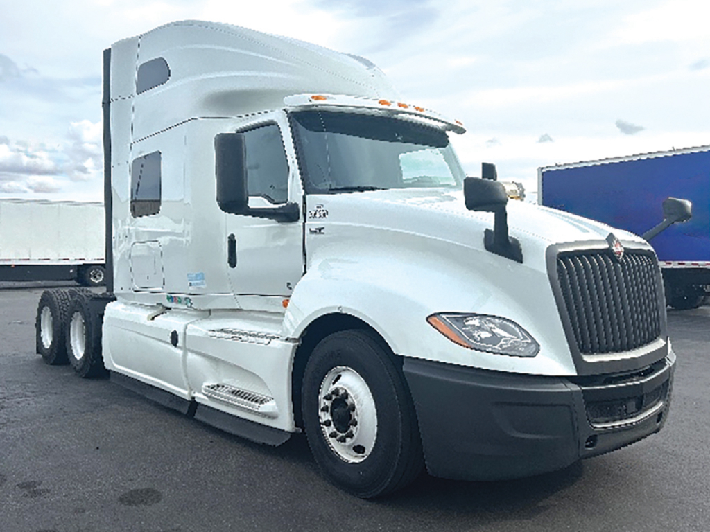 International LT625 sleeper cab truck in white angled side view showing tractor with aerodynamic mirrors and dual rear wheels.