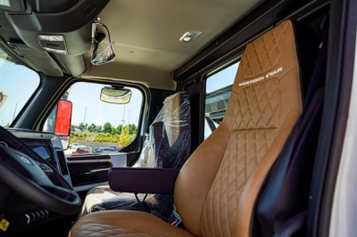 Interior cab of a 2027 Western Star 47X showing tan diamond-stitched seat with 'western star' embroidery and driver cabin features.