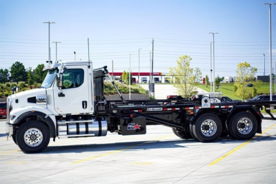 Western Star 47X rolloff truck in pickup lot, white cab, long black trailer chassis with hydraulic hoist and multiple axles.