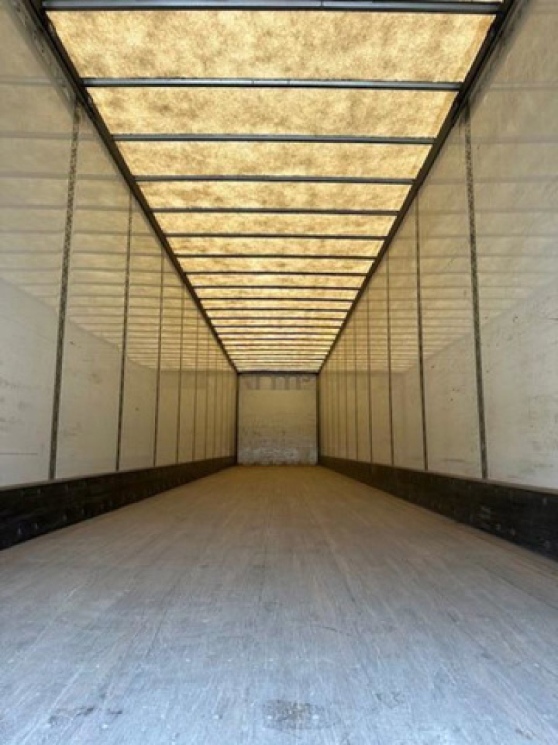 Trailer interior showing long empty storage trailer with illuminated ceiling panels and white walls, Wabash van.