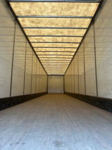 Trailer interior showing long empty storage trailer with illuminated ceiling panels and white walls, Wabash van.