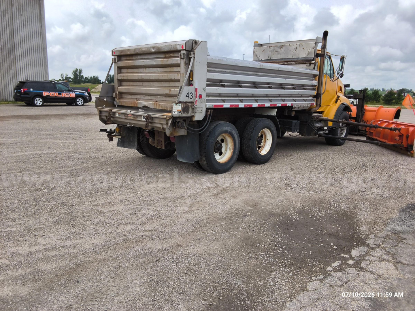 Dump truck rear view showing cargo bed and tandem rear axles with white rims and mud flaps.