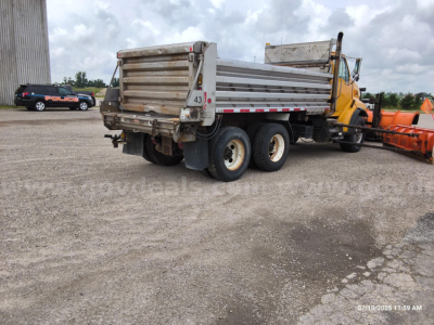 Dump truck rear view showing cargo bed and tandem rear axles with white rims and mud flaps.