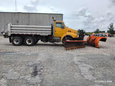 Dump truck with front-mounted snow plow blade and snow equipment attached, yellow cab, white dump bed, side view showing dual rear axles and mounted storage box.
