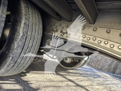 Trailer undercarriage showing riveted steel framework and wheel, with hydraulic drop mechanism visible.
