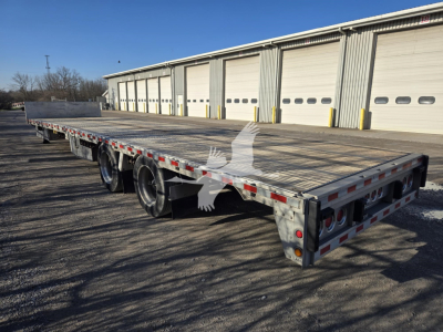Flatbed trailer in 2019 Reitnouer Dropmiser with wood deck and triple-axle configuration, rear dual lights, and reflective safety markings.