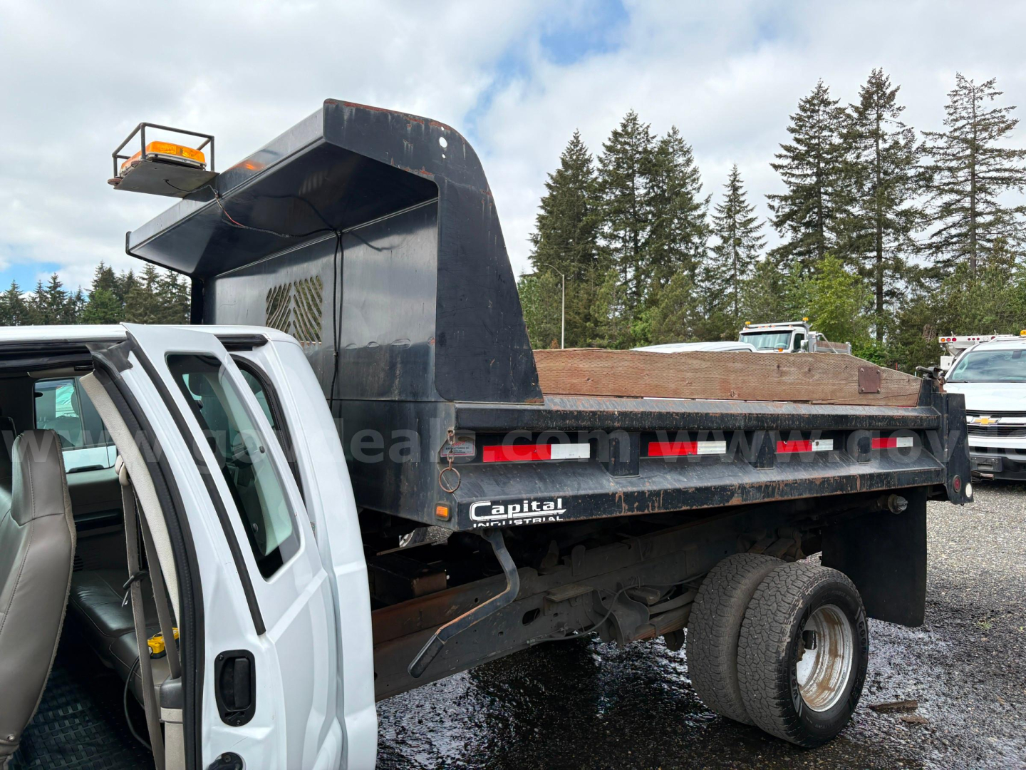 Truck bed of a white Ford F350 dump truck showing a Capital dump bed and loaded dirt in the bed.