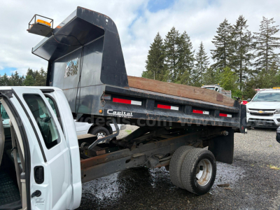 Dump bed truck rear showing dump body and chassis with wheel, side rails, and taillights; Ford F-350 truck bed under elevated dump container.