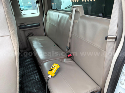 Ford F-350 truck interior rear bench seat with seat belt and a yellow diagnostic tool connected to a cord.