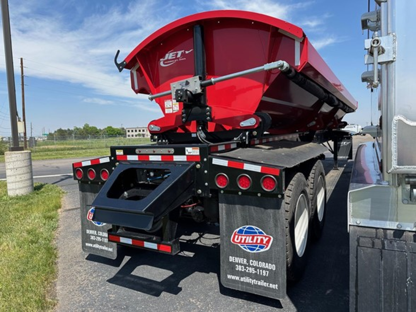 Red Jet Jet side dump trailer in trailer bed with black chassis and multiple rear LED lights.