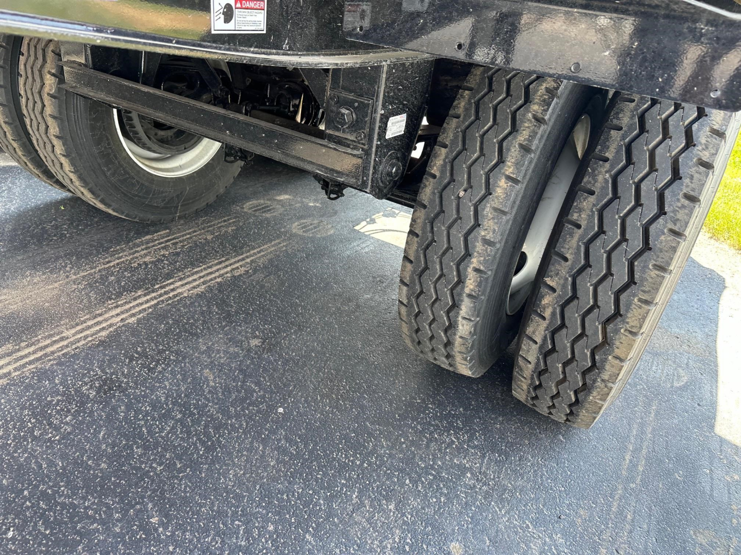 Jet side dump trailer underside and dual rear tires showing suspension and frame components.