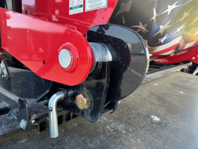 Docking hitch and corner of red trailer frame showing hitch pin and chain loop with black protective cover.