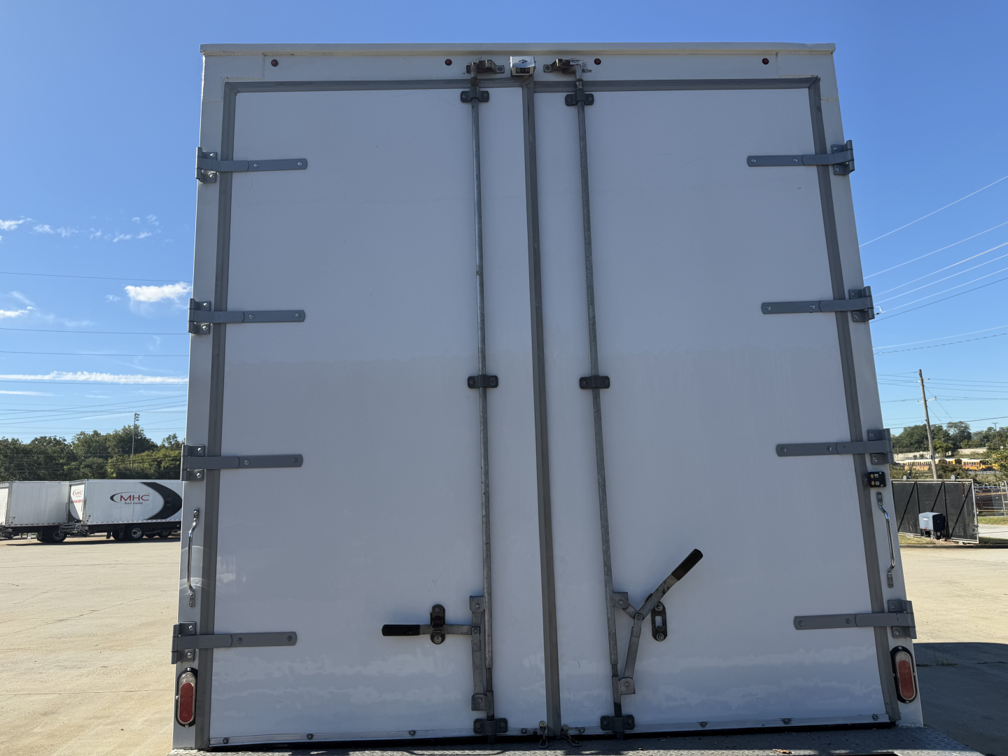 Kenworth T270 box truck rear doors showing dual vertical hinges and latches, with rear bumper and lights visible.
