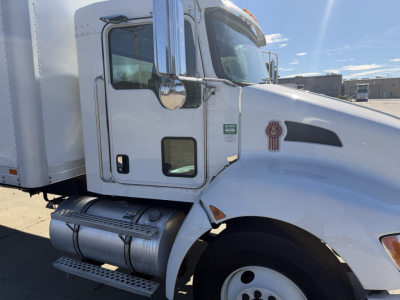 Kenworth T270 truck cab side view showing white exterior, chrome exhaust/air intake, fuel tanks, and Kenworth emblem on door.