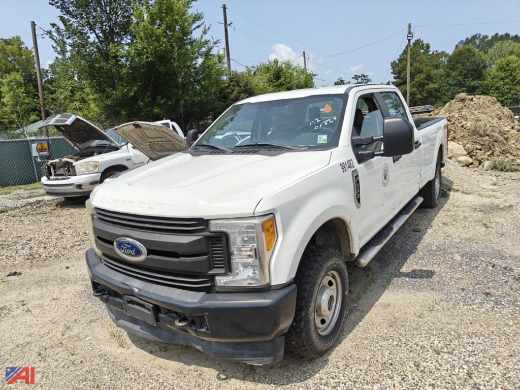 White 2017 Ford F-250 Super Duty regular cab/crew cab pickup truck with service decals, parked on gravel; front grille Ford badge, chrome bumper, open hood on a car lot.
