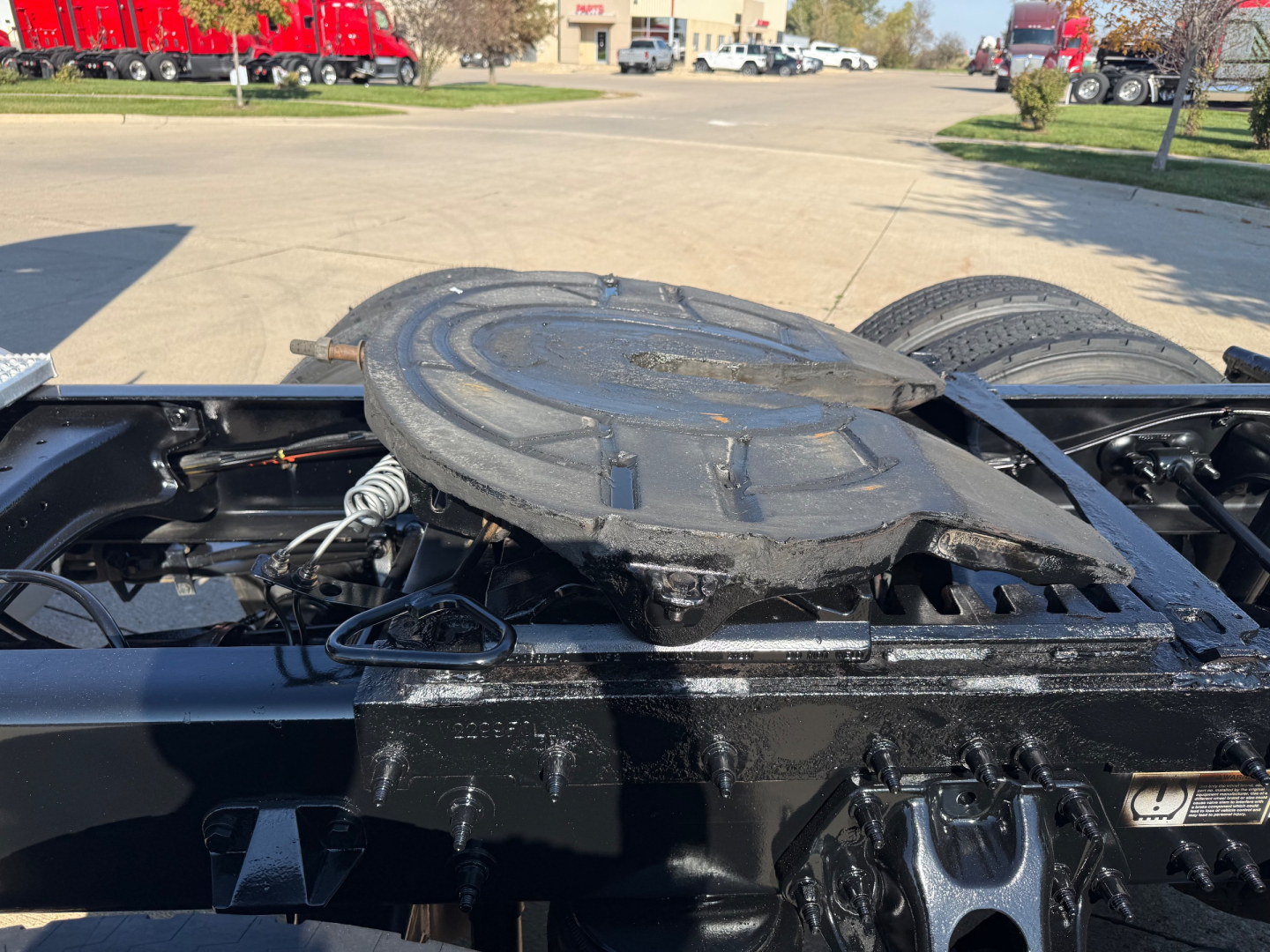 Truc k tractor cab area showing fifth wheel mounting plate and surrounding chassis with spare wheel cradle on a Peterbilt 579. Visible components include black metal frame, connectors, and wiring near the fifth wheel.