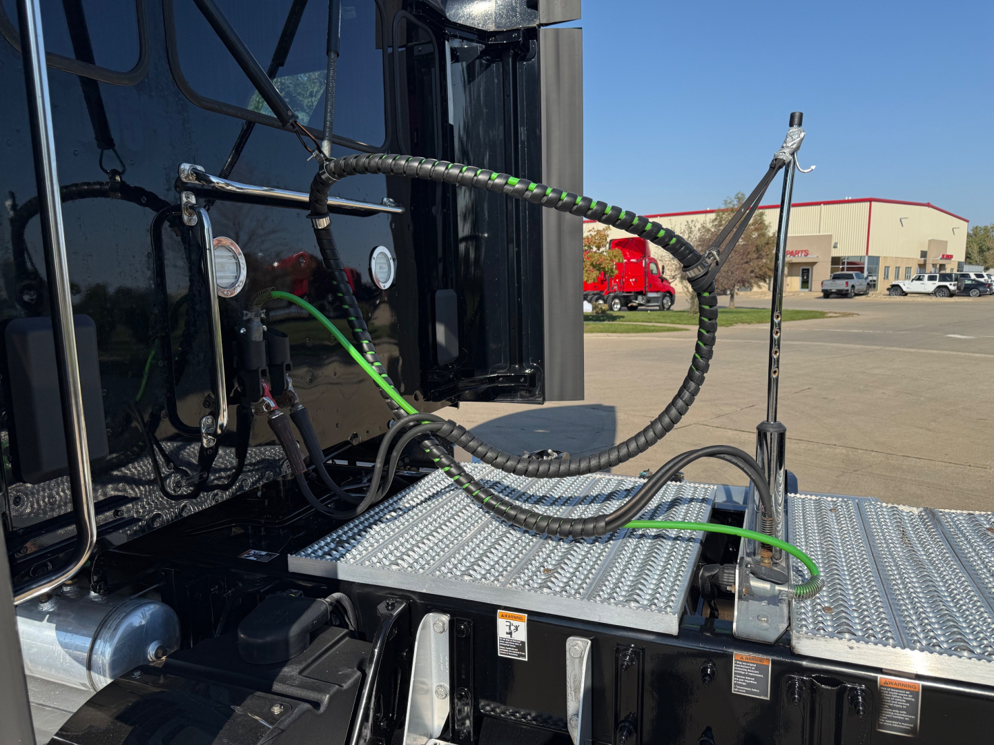Peterbilt 579 access steps and electrical cables on driver side with metal diamond-plate step and cab exterior visible.