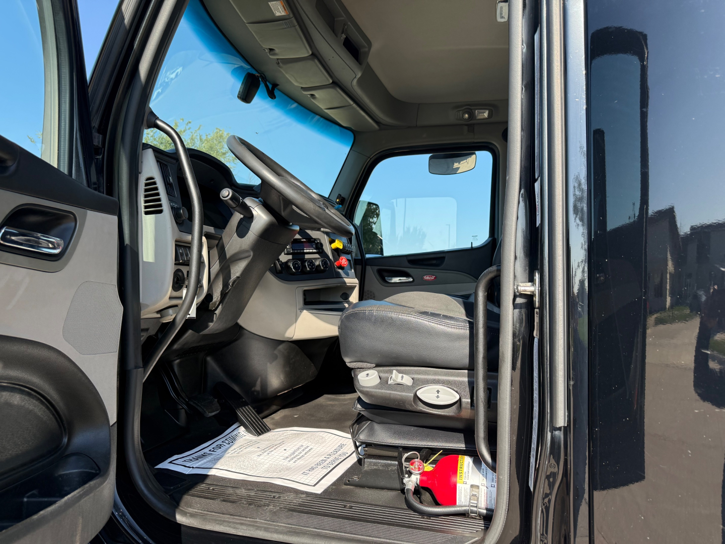 Peterbilt 579 truck interior cabin view showing driver seat and dashboard with steering wheel and pedals.