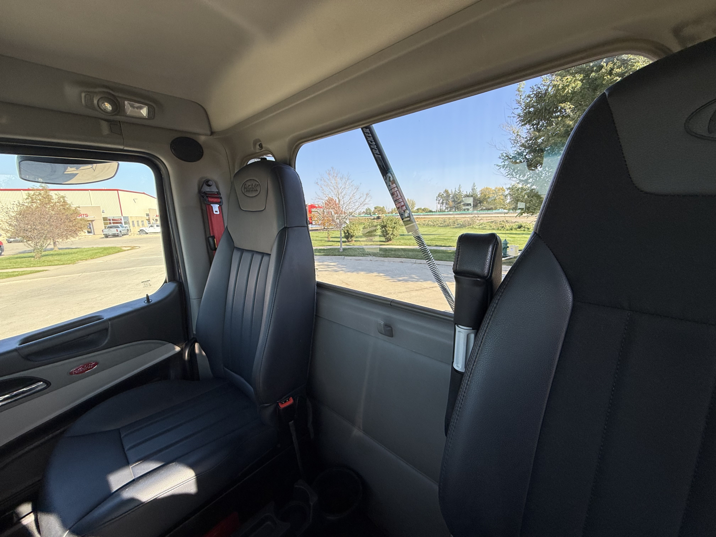 Peterbilt 579 cab interior view showing driver and passenger seats, window, and interior trim.
