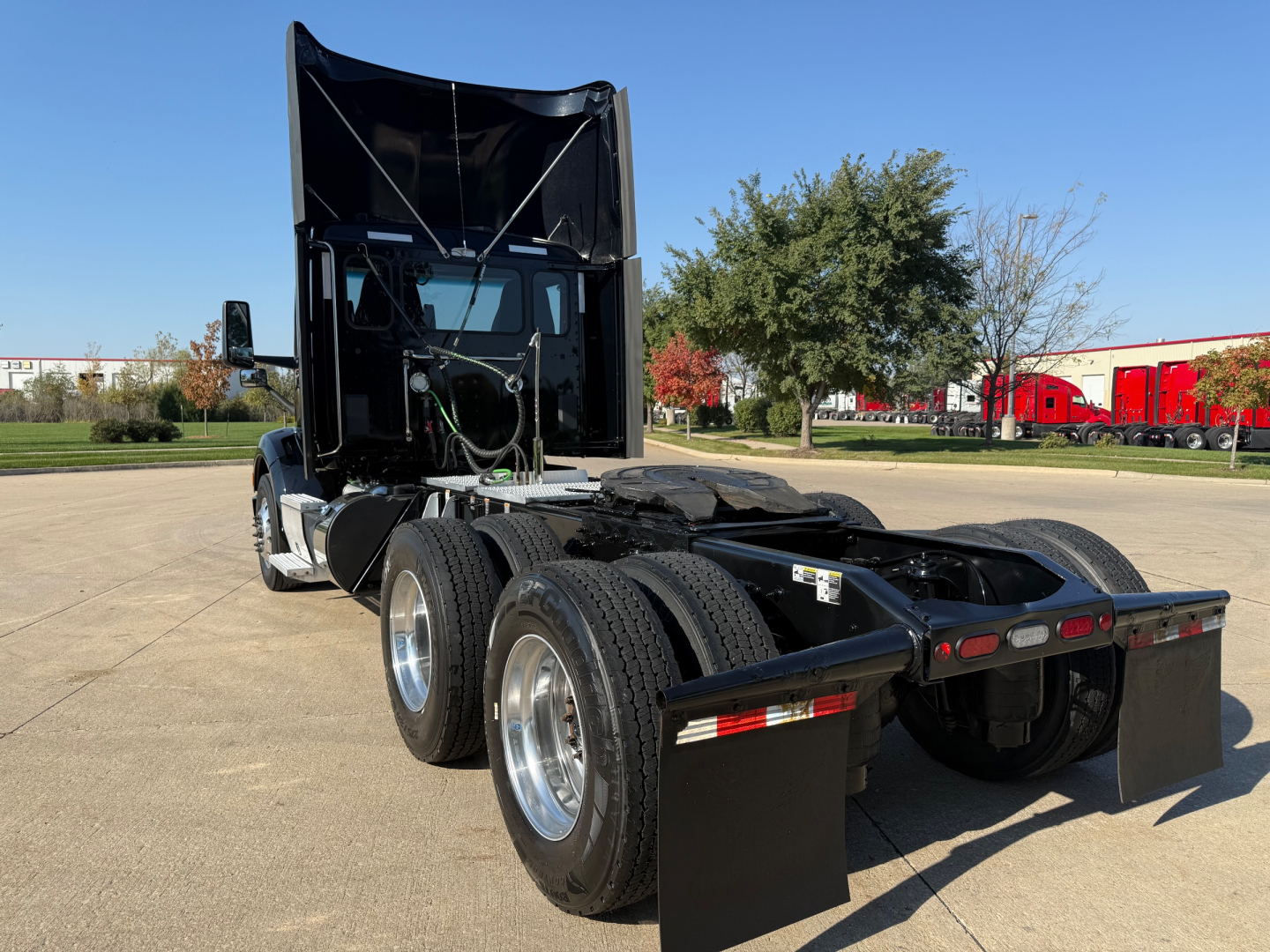 Peterbilt 579 semi truck in a lot with sleeper cab raised hood and dual rear axles showing five tires, chassis and fifth wheel area visible.