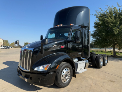 Peterbilt 579 conventional daycab tractor in black, front angled view with raised sleeper cab, chrome grille, dual rear axles, and fuel tanks visible.