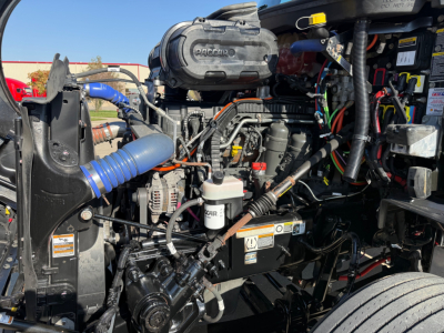 Peterbilt 579 engine bay showing air intake, hoses, wiring harness, hydraulic lines, and fuel/wilter filters in view.