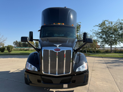 Peterbilt 579 tractor cab front view showing grille, headlights, and aerodynamic mirrors in a parking lot.