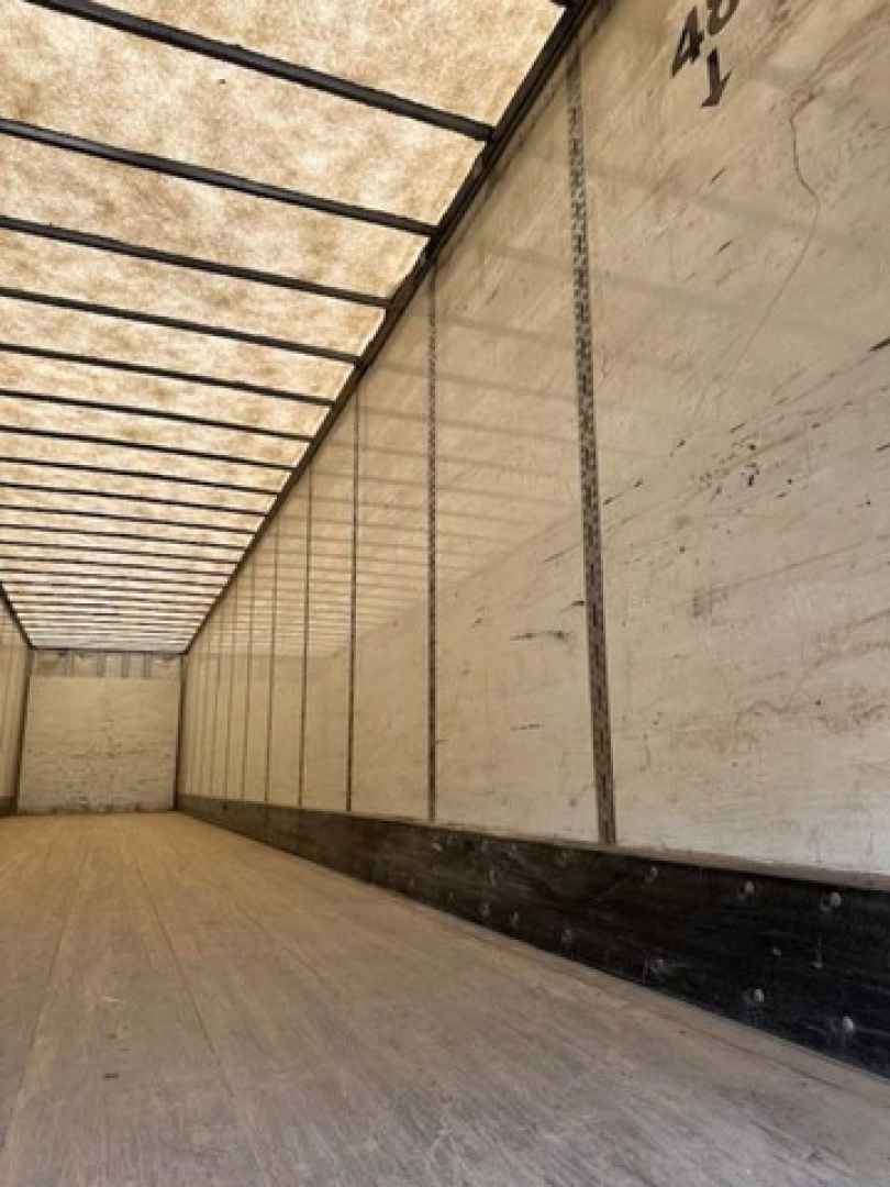 Inside of a 2014 Wabash Van trailer showing long interior with wooden floor and white side walls.