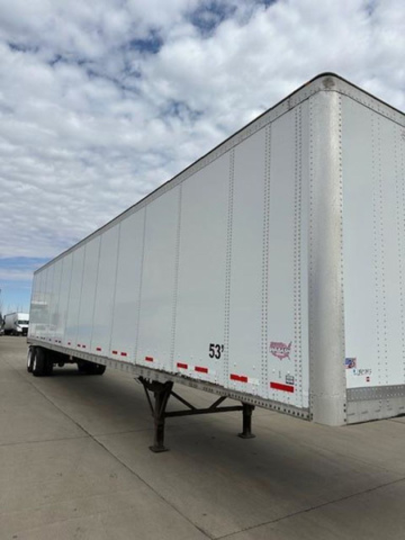 Trailer side view showing white 53' Wabash van semi-trailer with landing gear and rear DOT stickers.