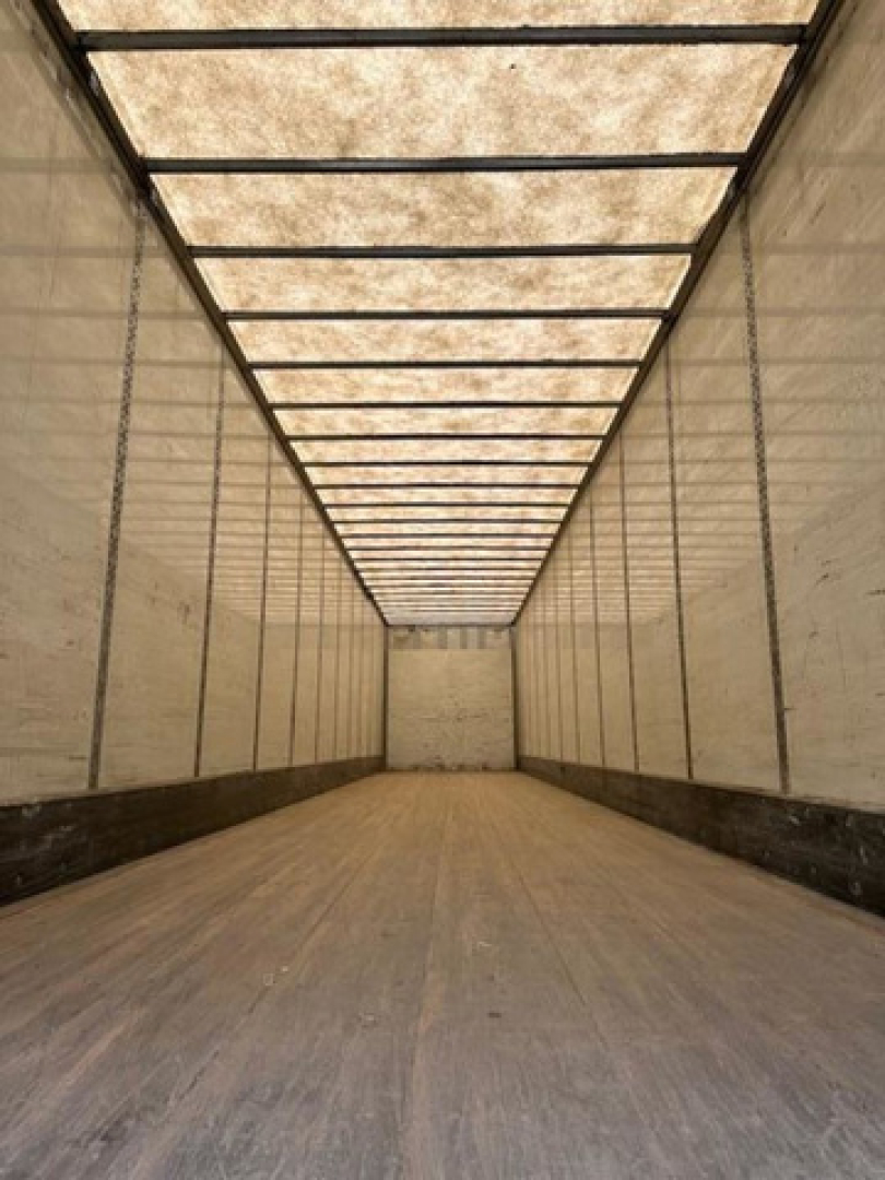 Interior view of a 2014 Wabash van trailer with empty cargo area, long box, wooden floor, and side walls. No visible text legible.