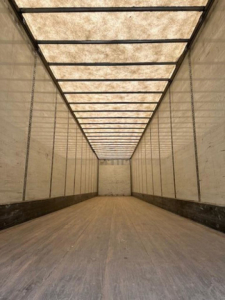 Interior view of a 2014 Wabash van trailer with empty cargo area, long box, wooden floor, and side walls. No visible text legible.
