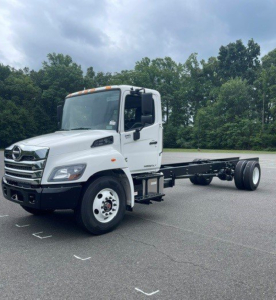 White 2027 Hino L7 cab chassis truck with empty rear frame, side view showing cab details and front grille.