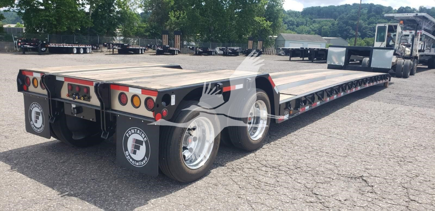 Fontaine Renegade X20 trailer in a parking lot, dual tandem rear section visible, with long lowboy flatbed and multiple wheel axles; rear lights and reflective tape; branding decals visible on mud flaps.